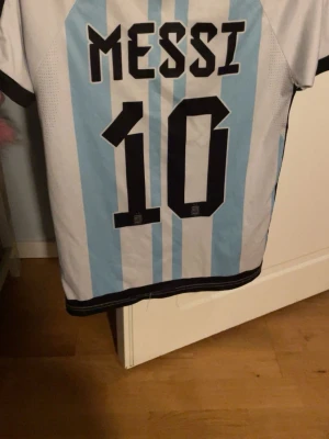 T-shirt Fotbollströja Argentina - Bilderna visar en argentinsk fotbollströja med Messi och nummer 10. Sitter som storleken säger.