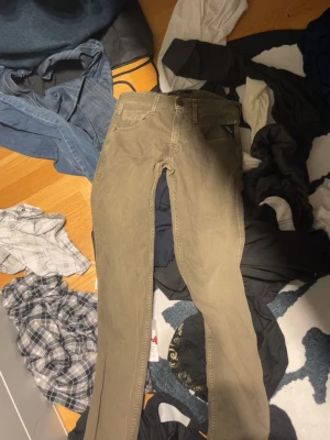 Beiga Replay byxor med slim fit - Säljer ett par snygga beiga byxor från Replay med klassisk femficksdesign och diskret logga på fickan. Byxorna har slim passform och raka ben, perfekta till en avslappnad stil. Materialet är mjukt och skönt bomullstyg.