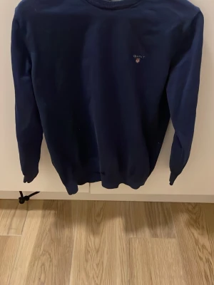 Gant Tröja Marinblå - Säljer en stilren marinblå tröja från Gant i stretchig bomull. Klassisk rund halsringning och diskret Gant-logga broderad på bröstet. Perfekt till jeans eller chinos för en clean look. Skickas dagen efter köp. Hör av er om ni har några frågor!