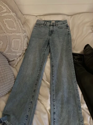 Ljusblå wide jeans från Understatement - Säljer ett par ljusblå jeans från Understatement med riktigt breda ben och klassisk femficksmodell. Jeansen har hög midja och är tillverkade i ett mjukt denimtyg. Perfekta för dig som gillar en avslappnad och trendig look.