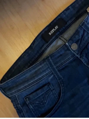 Replay Anbass Slim Jeans - Snygga blå jeans från Replay med klassisk femficksdesign och stilrena sömmar på bakfickorna. Perfekta för en avslappnad look. Riktigt feta jeans med fet tvätt som är sparsamt använda, slim passform i storlek 29/32! Vid funderingar eller frågor är det bara att höra av sig!