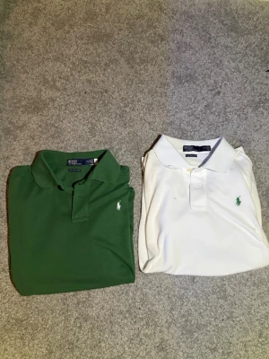 Pikétröjor från Ralph Lauren, grön & vit - Två klassiska pikétröjor från Ralph Lauren, en i djup grön och en i fräsch vit. Båda har den ikoniska broderade loggan på bröstet och krage med knappar. Modellen är normal passform och materialet är mjuk polyesterblandning. Perfekt till jeans eller shorts. Gammal model. Storlek L i barn. Personen på bilden 177. Använd få tall gånger