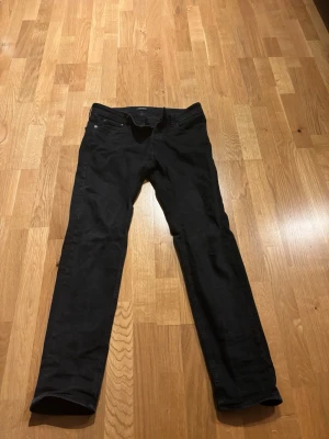 Svarta Jack N Jones jeans  - Säljer ett par svarta jeans med klassisk femficksdesign och slim/straight passform. Jeansen har normal midja och är tillverkade i bomull. Storleken är 32/34