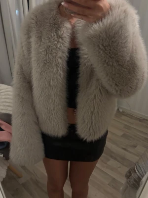 Beige pälsjacka från Gina Tricot - Supermjuk och fluffig beige pälsjacka från Gina Tricot. Jackan har lång ärm, rak passform och är i fuskpäls med bred krage. Perfekt för dig som vill sticka ut och hålla dig varm med stil. Säljes i storlek S.
