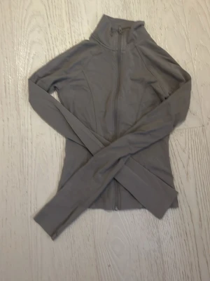 Grå zip hoodie från Gina Tricot - Säljer en grå hoodie från Gina Tricot i storlek XXS. Tröjan har hel dragkedja framtill, hög krage och långa ärmar. Perfekt till chill dagar eller när du vill ha en enkel och clean look. Materialet känns mjukt och stretchigt.