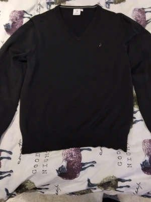 Svart v-ringad tröja från Boomerang - Klassisk svart v-ringad tröja från Boomerang i mjuk bomullsblandning. Diskret broderad logga på bröstet och ribbade muddar vid ärmslut och nederkant. Perfekt till lager på lager och enkel att matcha med allt.