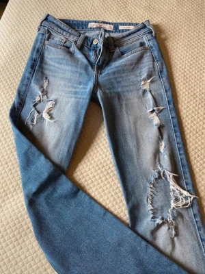 Jeans med slitningar - Suuuper snygga jeans med slitningar och bootcut stil från hollister i storlek 25/34, aldrig använda därav i nyskick ☺️