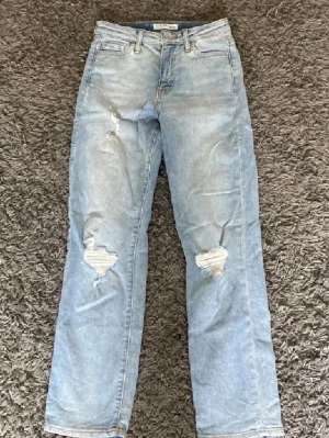 Ljusblå slitna raka jeans - Säljer ett par ljusblå jeans straight och slitningar på båda knäna. Jeansen har klassisk femficksmodell och normal passform. Perfekta för en avslappnad och trendig look. Medelhög midja!❤️