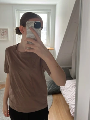 Brun basic t-shirt i bomull - Enkel brun t-shirt i mjuk bomull med rund hals och korta ärmar. Modellen är rak och passar perfekt till jeans eller shorts. Stilren och clean look som funkar året runt.