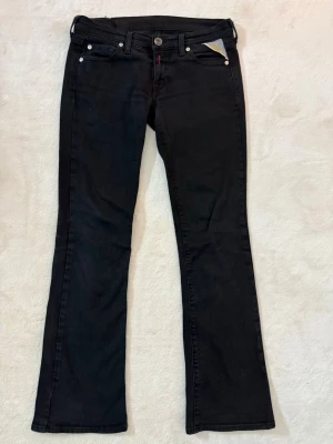 Svarta Replay bootcut jeans - Säljer ett par svarta Replay jeans med bootcut passform. Klassisk femficksmodell med snygga detaljer på bakfickorna och Replay-lapp i bak. Jeansen är i bootcut modell med låg midja. Köpta second hand för ett par år sen. Midjemått 38cm rakt över och innerbenslängd 78cm.🫰