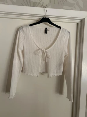 Vit croppad kofta med knyt - Söt vit kofta från Hm som  aldrig är använd. Superfin över ett linne eller klänning💕💕 Skriv för frågor eller fler bilder