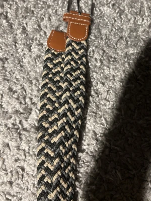Svart och beige flätat bälte - Säljer en svart och beige bälte som är flätat. Lite tecken på användning annars bra skick. Säljs för det inte används något mer. Säljs för 50kr. Kontakta mig om du har frågor.