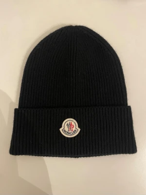 Moncler mössa  - Svart moncler mössa i fint skick använd 5 gånger så den ser ny och fräsch ut