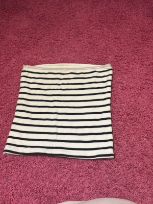 Randig kortkjol från BikBok - Säljer en vit och svart kortkjol från BikBok med klassiska horisontella ränder. Kjolen har en rak passform och är gjord i mjukt bomullsmaterial som känns skönt mot huden. Perfekt för dig som gillar enkel och stilren design.