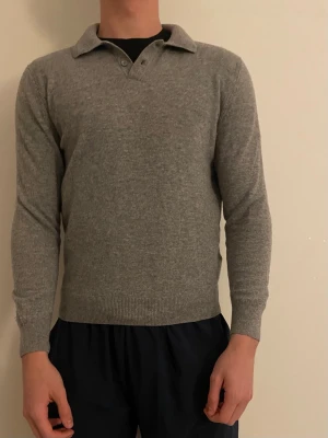 Grå stickad långärmad pikétröja från Zara - Klassisk grå pikétröja från Zara i mjuk ullmix. Tröjan har krage och långa ärmar, perfekt för lager på lager under höst och vinter. Skulle säga att den krympt lite i tvätten och passar därför både L och M Enkel och stilren design som funkar till det mesta.