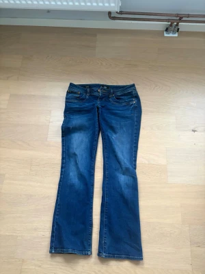 Blå bootcut jeans LTB Valerie W27 L30 - Säljer ett par blå jeans från LTB, modell Valerie, i storlek W27 L30. Jeansen har en klassisk femficksdesign, bootcut-ben och snygga slitningar. Tillverkade i tåligt denim med kontrastsömmar och låg midja. Köpta för 799 