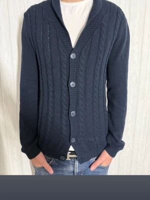 Mörkblå stickad kofta med knappar - Snygg mörkblå stickad kofta. Storlek M.  Perfekt att slänga på över en t-shirt. Använd ett fåtal gånger. Vid fundering är det bara att hojta till ! 