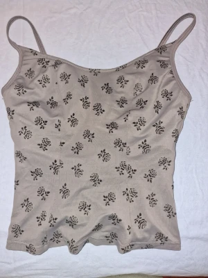 Grått linne - Sött linne med ett blommigt mönster. Perfekt för varma dagar eller som ett lager under andra kläder. Storlek 38 men liten i storleken.