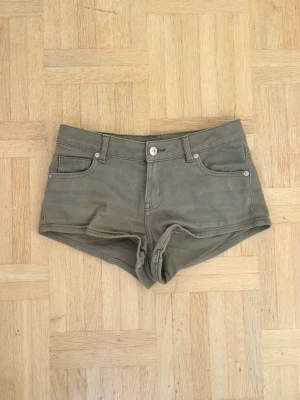 Olivgröna midwaist shorts💖 - Säljer ett par olivgröna shorts med klassisk femficksdesign och bälteshällor. Modellen är kort och har en rak passform med knapp och dragkedja framtill. Perfekta för varma dagar och enkla att matcha med olika toppar.