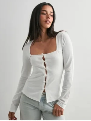 Vit långärmad topp med knyt - Säljer en vit långärmad topp med fyrkantig urringning och flera små knyt framtill som stängning. Toppen har en figurnära passform och är tillverkad i ett mjukt bomullsmaterial. Perfekt att styla med jeans eller kjol. Har aldrig användt och den är helt ny dock har jag inte tagit bild på den så detta är en bild från nellys hemsida ifall ni undrar över något eller vill ha bild på toppen skriv gärna!(pris kan diskuteras❤️)