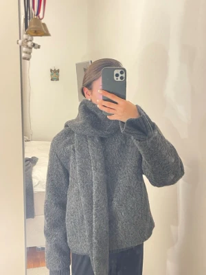 Kort kappa med bouchléhalscaf - Säljer en mörkgrå, fluffig kort kappa från Zara i storlek XS. Jackan har en inbyggd scarf så man kan bära på olika sätt. Köptes för 699kr, säljer för 419kr.