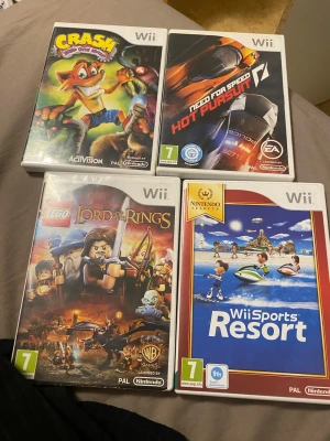Nintendo Wii spelpaket (4 spel) - Fyra populära Wii-spel: Crash Mind Over Mutant, Need for Speed Hot Pursuit, LEGO Lord of the Rings och Wii Sports Resort. Alla fodral ser ut att vara i gott skick, perfekta för familjespel och samlare.