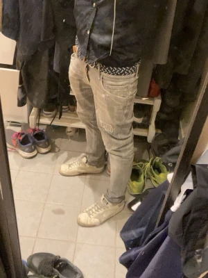Replay grå slim jeans med slitningar - Säljer ett par gråa Dsquared jeans i slim fit med snygga slitningar och patchdetaljer på framsidan. Jeansen har klassisk femficksdesign, normal midja och raka ben. Materialet är mjukt jeans-tyg som sitter skönt och ger en avslappnad look.