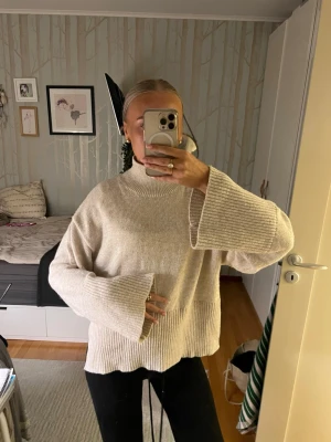 Beige stickad tröja från Gina Tricot - Supermysig beige stickad tröja från Gina Tricot med breda, långa ärmar och hög hals. Tröjan har ribbade detaljer vid ärmslut och nederkant, och en loose fit som ger en chill vibe. Perfekt att slänga på sig när det är kallt ute. Passar Xs-M🥰