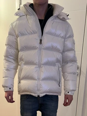 Vit Moncler pufferjacka med huva - Säljer denna vita moncler jacka som jag endast använt ett fåtal gånger, inga defekter alls. Den är i storlek L men skulle säga den passar M med beroende på hur man vill att den ska sitta. Skriv privat för fler frågor eller bilder! 