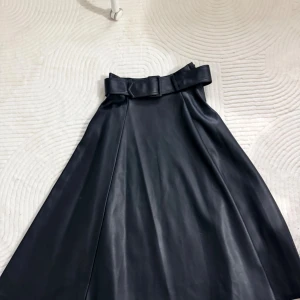 Svart långkjol i skinnimitation H&M - Snygg svart långkjol från H&M i skinnimitation med hög midja och brett bälte. Kjolen har en A-linjeformad siluett som ger en cool och trendig look. Perfekt för dig som vill sticka ut med en edgy vibe.