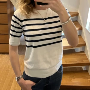Randig vit tröja från Kappahl XS - Vit tröja från Kappahl i storlek XS med blåa horisontella ränder. Tröjan har rund halsringning, ribbade muddar och halvlånga ärmar.