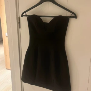 Svart axelbandslös kortklänning - Supersnygg svart axelbandslös klänning med hjärtformad urringning och figurnära passform. Man ser ut som Kim K i denna, helt sjuk. Passar till nyår