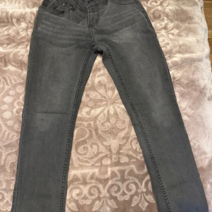 Levi's 512 Slim Tapered grå jeans - Snygga grå Levi's 512 Slim Tapered jeans med klassisk femficksdesign och dragkedjegylf. Jeansen har en smal passform som smalnar av nedtill och är tillverkade i mjukt denimtyg. Perfekta för dig som gillar en modern och stilren look.
