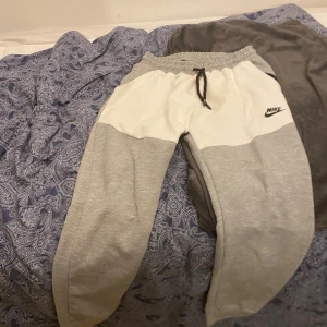 Nike gråvita mjukisbyxor med snörning - Snygga mjukisbyxor från Nike i grått och vitt med svart snörning i midjan och logga på vänster sida. Priset kan diskutera vid snabb affär.