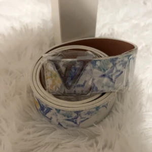 Bälte - 🤍 Vit/blå mönstrat bälte – 110 cm  Unikt bälte med vit bas och inslag av blått och gult. Fräsch design som sticker ut och lyfter din outfit — perfekt för vår och sommar.  📏 Längd: 110 cm 🎨 Färgglad och trendig stil 🚚 Fraktas och skickas snabbt! 💰 Pris: 279 kr