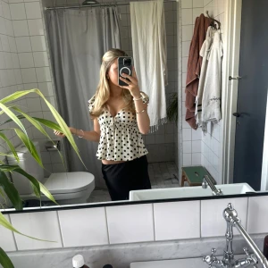 Vit prickig blus - Supersöt vit blus med svarta prickar, knappast använd. Den är i storleken M men passar på mig som vanligtvis har xxs-xs då den har ett band som man knyter så man kan välja själv hur tajt den ska sitta!🥰