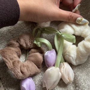 Fluffiga diadem med tulpaner - Två fluffiga diadem i beige och brun med söta tyg-tulpaner i lila och vitt, dekorerade med gröna sidenband. Perfekt för att ge din look en gullig och unik touch. Materialet är mjuk pälsimitation och siden.