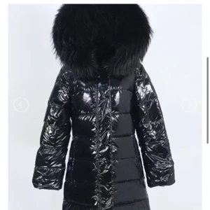 Svart lång pufferjacka med päls - Säljer en svart, glansig pufferjacka med stor fluffig huva och pälsdetalj. Aldrig använd inköpt för 3399:- endast testat. Köpt på luxeswe.com