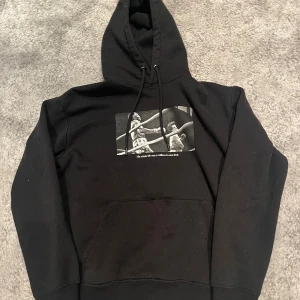 Svart Rocky Balboa hoodie Pull&Bear XS - Svart hoodie från Pull&Bear med Rocky Balboa-tema. Framsidan har ett boxningsmotiv och texten 'His whole life was a million-to-one shot'. Baksidan har stor text 'ROCKY BALBOA THE ITALIAN STALLION'. Huva med snörning och känguruficka. Perfekt för dig som älskar filmklassiker.