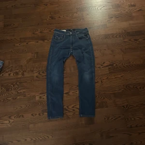 Replay Hyperflex Anbass jeans blå - Snygga Replay Hyperflex Anbass jeans i blå färg med slim fit-passning. Klassisk femficksdesign, ljusa slitningar och kontrastsömmar. Stretchigt jeansmaterial som ger grym komfort och rörelsefrihet. Perfekt för dig som gillar stilrena och moderna jeans. Kom gärna med prisförslag.