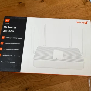 Mi Router AX1800 - Xiaomi Mi Router AX1800 med Wi-Fi 6, Qualcomm 5-core processor och hastigheter upp till 1775 Mbps. Stöd för WPA3-säkerhet och mesh-nätverk. Produkten ser ut att vara i nyskick, förpackningen är obruten och utan synliga skador.