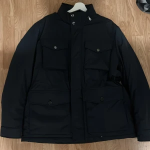 J.Lindeberg-Acer Padded Jacket-Navy - Helt oanvänd jacka från J-Lindeberg, säljes på grund av att storleken är för stor. Ny pris: 4000kr.                                                         Marinblå jacka från J Lindeberg håller dig torr och mysig under hela säsongen. Den är tillverkad av en vattenbeständig polyesterblandning fri från PFC och det återvunna polyesterfodret och Primaloft-vadderingen gör den mycket varm och även miljövänlig. 