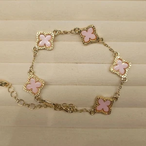 Guldfärgat armband med rosa clover - Superfint armband med guldfärgad kedja och fem fyrklöverformade länkar i ljusrosa emalj. Varje länk har en dekorativ kant som ger en lyxig känsla. Perfekt accessoar för att lyfta din outfit med en söt och trendig detalj.