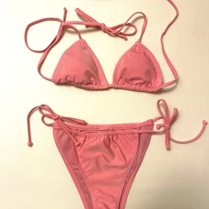 NA-KD rosa bikini  - Supersöt rosa bikini från NA-KD i klassisk trekantsmodell med knyt i sidorna. Aldrig använd, endast lappar bortklippta. Den är jättefin och är perfekt till sommaren!