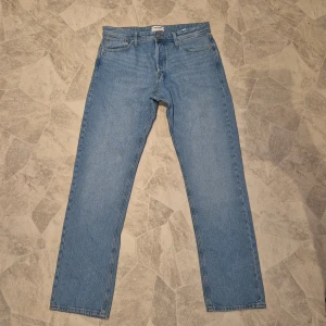 Ljusblå jeans från Jack & Jones 33/34 - Klassiska ljusblå jeans från Jack & Jones i relaxed modell. Byxorna har fem fickor, gylf med knappar samt snygga kontrastsömmar. Perfekta för dig som gillar en enkel och tidlös stil. Tillverkade i jeansmaterial.
