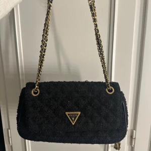 Väska  - Svart och lite glittrig axelremsväska från guess som är jättefin och i ett bra skick. Den är inte sönder någonstans de ända man kan se är att den börjar bli lite knottrig men annar jättefin 💕accepterar nästan alla prisförslag så det är bara att lägga ett.