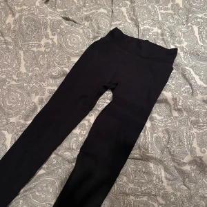 Svarta ribbade leggings från STRONGER - Svarta leggings från STRONGER med ribbad struktur och hög midja. Tillverkade i stretchigt material med 94% polyamid och 6% elastan, perfekta för träning eller chill. Snygg passform som sitter tajt och följer kroppen.