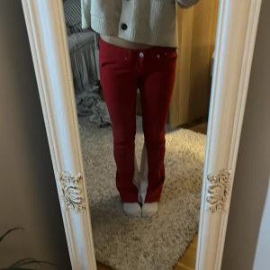 Röda bootcut byxor med vit slits - Snygga röda bootcut byxor med vit slits längs insidan av benen. Byxorna har låg midja, klassisk och en extra dragkedja baktill. dom är väldigt stretchiga och sydde om de själv från skinny till bootcut. W 26 L 32. pris kan diskuteras❣️