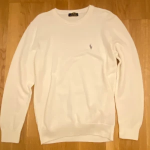 Vit tröja från Polo Ralph Lauren - STOR STORLEK MEN DEN SITTER SOM EN M-L.       Klassisk vit långärmad tröja från Polo Ralph Lauren i 100% bomull. Tröjan har rund halsringning, ribbade muddar och den ikoniska broderade loggan på bröstet. Perfekt för en clean och stilren look.