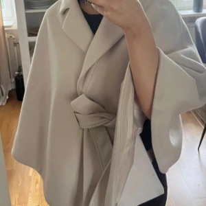 Poncho - Superfin Design by si liknande poncho / kappa från märket Bubbleroom. Den är beige och i storlek S. Det finns även en tillhörande pälskrage, vilken är avtagbar som bilden visar💕💕